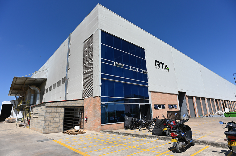 Vista general de la planta de RTA en Cartagena. Se visualizan algunos vehículos en la zona del parqueadero y un cielo azul al fondo